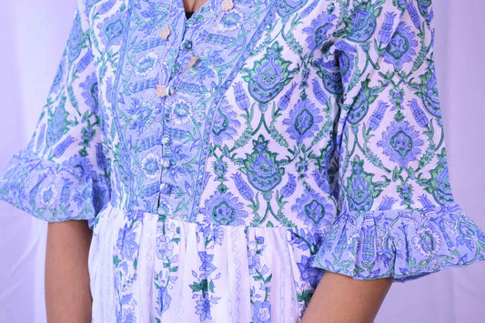 Close-up: Blue Brunnera floral block print organic cotton dress with buttoned V-neck and ruffled sleeves.